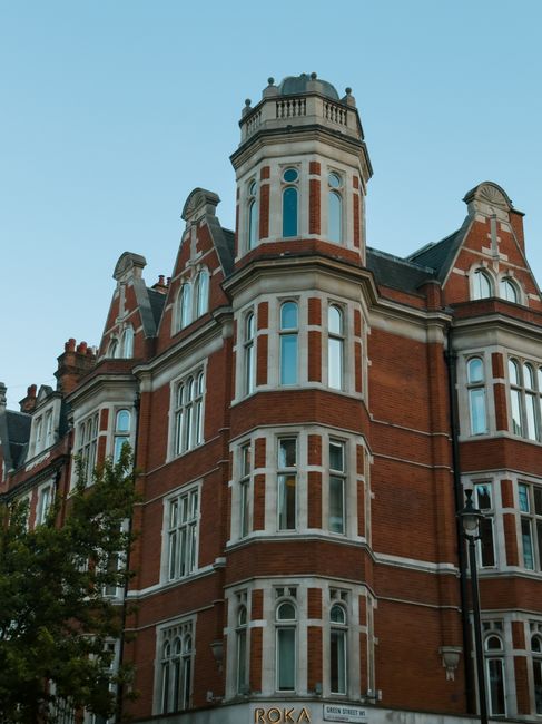 Photograph of a historic multi-storey building in Knightsbridge with ornate stone architecture, large arched windows at street level, and decorative façade detailing. The building features a vertical